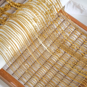 Minimalist gold stainless steel necklaces and bracelets displayed in a luxury wooden tray