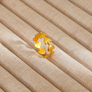 Macro view of golden leaf-shaped open ring displayed in a beige velvet jewelry box