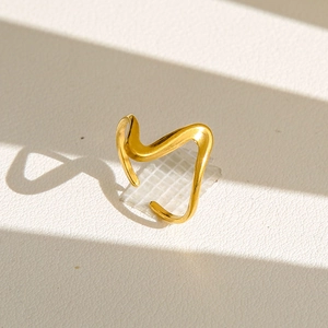Détail d'une bague dorée ondulée minimaliste avec finition polie et design fluide