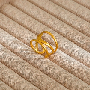 Detailed view of multilayer hollow geometric gold plated ring on a textured jewelry tray