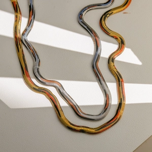 Collares de cadena de serpiente en oro y plata con texturas abstractas negro y naranja