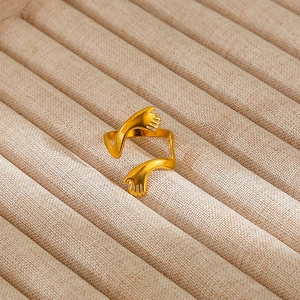 Detailed macro shot of a golden stainless steel embrace ring with polished finish