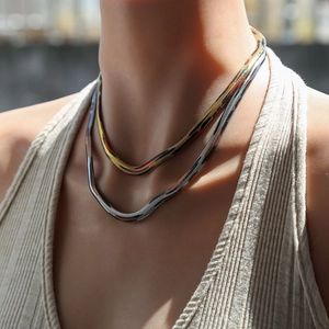 Detalle de collar de cadena de serpiente multicapa con degradado metálico de oro y plata