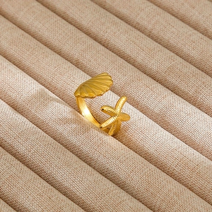 Detailed close-up of golden adjustable ring with seashell and starfish oceanic charms