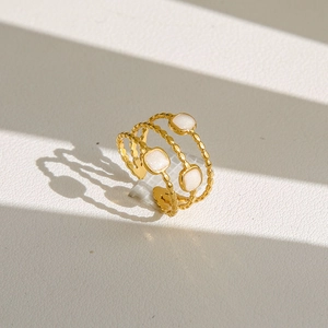 Détail macro de bague dorée multicouche avec anneaux texturés et accents de perles carrées