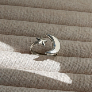 Gros plan sur les breloques étoile et lune polies d'une bague ajustable minimaliste