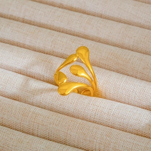 Macro di anello dorato con onde astratte e texture opaca su espositore in beige