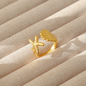 Dettaglio ravvicinato di stella marina e conchiglia placcati in oro 18k su anello aperto
