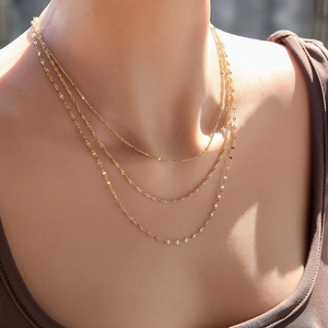 Vue détaillée de colliers superposés en acier inoxydable plaqué or 18k sur un mannequin
