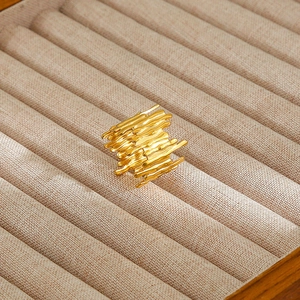 Macro shot of molten metal textured gold ring on beige linen jewelry box slot