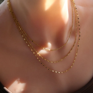 Détail de colliers triple rang en acier inoxydable plaqué or 18k avec sequins dorés