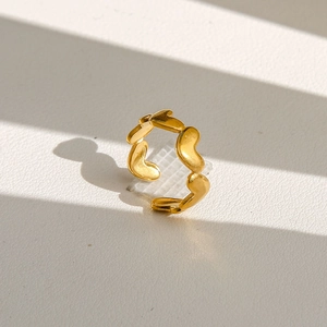 Détail macro d'une bague cœur plaquée or avec finition mate et jeux d'ombres artistiques