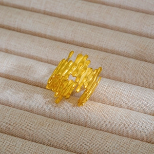 Dettaglio macro di un anello largo dorato con trama lavica e design aperto regolabile
