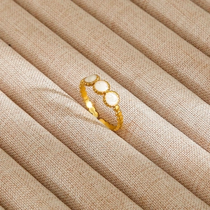 Detail of vintage gold ring with three white circular inlays and beaded edge accents