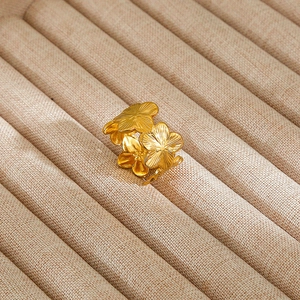 Detail of a gold flower ring with radial brushed texture on a brown linen display case