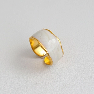 Dettaglio dell'anello vintage dorato con smalto marmorizzato e bordi ondulati