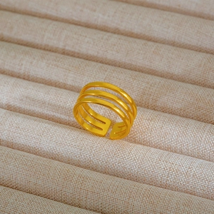 Dettaglio macro di anello regolabile a tre strati dorato su vassoio in velluto beige
