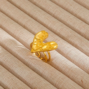 Close-up of golden hammered heart ring with adjustable double band on beige velvet tray