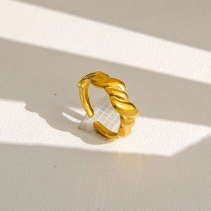 Détail macro d'une bague croissant torsadée dorée montrant l'anneau réglable et la texture