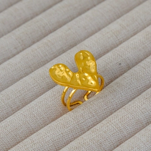 Dettaglio anello a cuore oro 18k con trama martellata su base in tessuto grigio