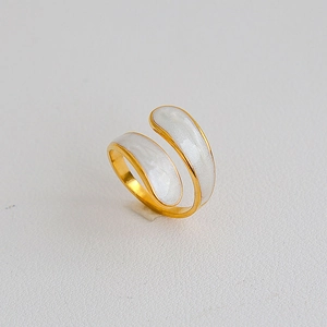 Dettaglio anello in acciaio placcato oro con design incrociato bianco perla lucido
