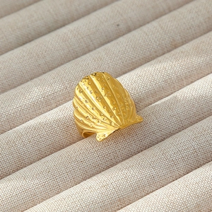 Macro di anello a conchiglia placcato oro con texture a coste su vassoio di beige