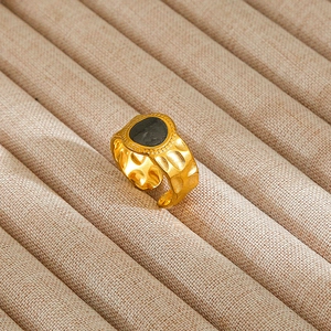 Detailed view of gold hammered ring with black stone inlay on velvet tray