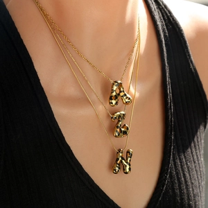 Collar dorado de tres capas con colgantes de letras de leopardo en chaleco negro