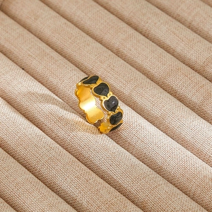 Macro shot of vintage style gold ring with black enamel hearts and pearl detail