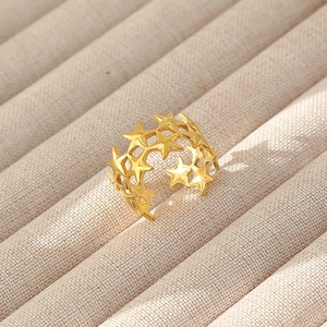 Dettaglio dell'anello aperto dorato con motivo a stelle su espositore per gioielli beige