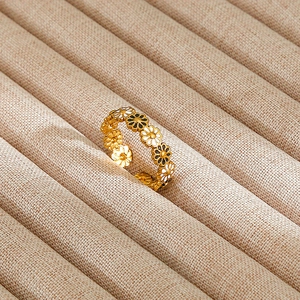 Detailed close-up of golden daisy ring with black and white enamel petals on jewelry box