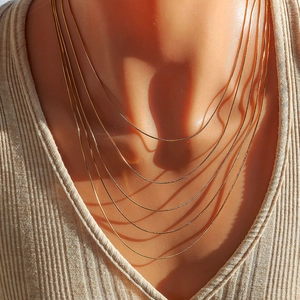 Détail d'un collier multi-rangs en acier inoxydable doré sur le cou d'un modèle