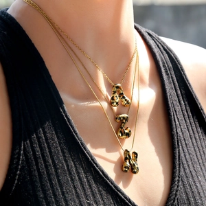 Primer plano de collares dorados con colgantes de letras en estampado de leopardo