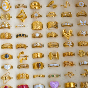 Collection of vintage gold rings with enamel and pearls displayed in a jewelry box