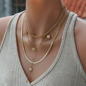 Detailed view of layered gold necklaces with star pendant and herringbone chain on model