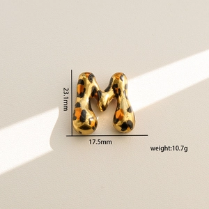 Detalle del colgante letra M dorado con estampado de leopardo y medidas del producto