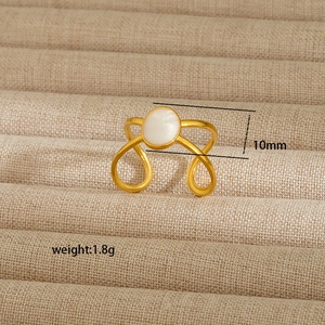 Detail view of gold stainless steel ring with white cat eye stone and cross curve design