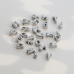 Dettaglio di perline a forma di lettere in argento lucido per gioielli fai-da-te