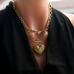 Detail of layered gold necklace with heart pendant and water drop crystal on a model