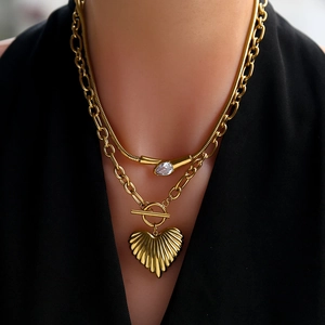 Detail view of double-layer gold necklace with heart pendant and pear-shaped drop stone