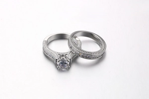 Detailed close-up of a silver-toned six-prong wedding ring set with milgrain edges and zircon