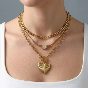 Three-layer gold necklace set with heart pendant and toggle clasp on a female model