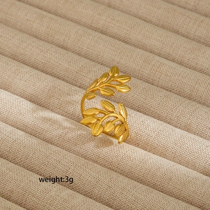 Detailed view of adjustable golden leaf ring weighing 3g on a beige fabric tray