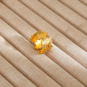 Macro shot of gold leaf textured adjustable ring on a beige luxury jewelry tray