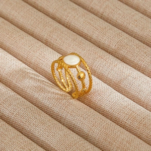 Detail of gold-plated twisted cable ring featuring a white round inlay on textured display