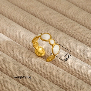 Detail view of gold irregular open ring with white enamel inlay on beige tray