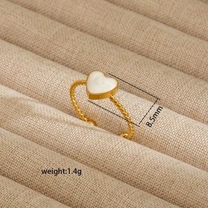 Detail view of gold twisted ring featuring an 8.5mm white heart inlay on jewelry box