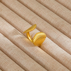 Detail of adjustable gold ring featuring two shell motifs on a beige jewelry display