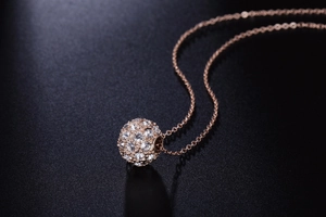 Détail du collier pendentif sphère en or rose avec micro-pavage de cristaux étincelants