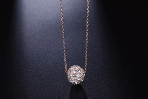 Gros plan du pendentif sphérique en or rose serti de cristaux de zircone scintillants